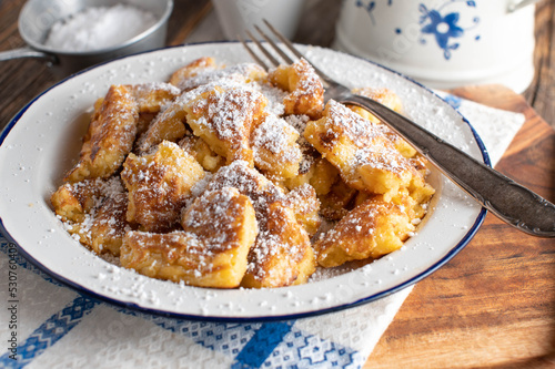 Traditional austrian kaiserschmarrn with powdered sugar on a enamel plate