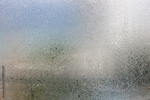 Misted glass, silver rain drops dew drops on transparent glass window. Wet misted glass with drops of water and dew.