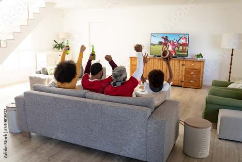 African american family supporting and watching tv with football match on screen