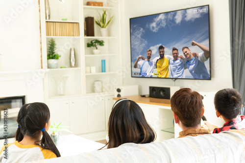 Diverse children watching tv with football match on screen