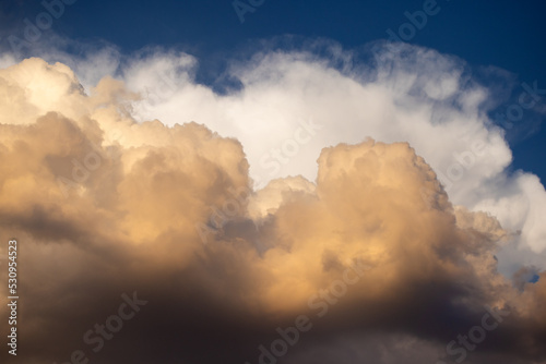 Multicolored white and yellow puffy clouds at sunset over blue sky