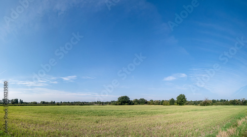 Pojedyncze chmury na niebie w krajobrazie wiejskim pośrodku obszarów wiejskich i pola, pora letnia Opolszczyzna, błękitne barwy