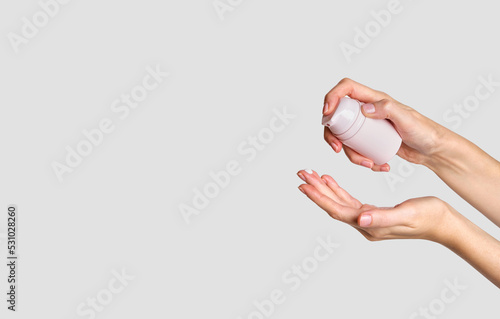 Woman applying lotion to hand. Cosmetic product branding mockup. Daily skincare and body care routine. Female hand holding cosmetic product mockup, close up.