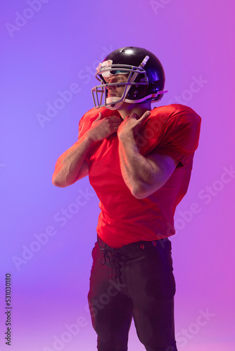 Caucasian male american football player wearing helmet with neon blue and purple lighting