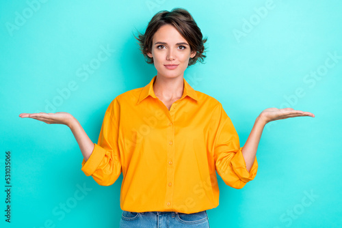 Portrait photo of young attractive pretty girl wear orange shirt hold palms balance choice isolated on aquamarine color background