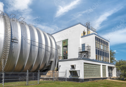 Exterior of an aeronautical research wind tunnel and white stucco and glass block control building, daytime, sunny with clouds, nobody