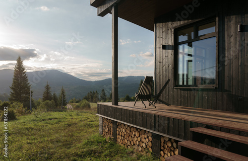 Black wooden chairs on cabin terrace with mountain view at sunset