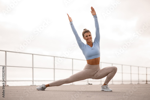 flexible woman stretching her body and doing side lunge exercises with hands up