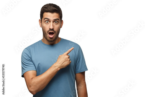 Young surprised man in blue t-shirt pointing right with his finger, shouting WOW. Shock content