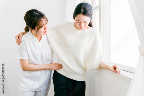 リハビリ治療で痛みに耐える女性と看護師（理学療法士・作業療法士） 