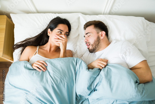 Annoyed woman suffering because of the bad breath of her husband in bed