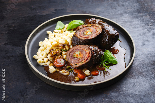 Traditional slow cooked German wagyu beef roulades with spaetzle served in spicy gravy sauce as close-up on a Nordic design plate