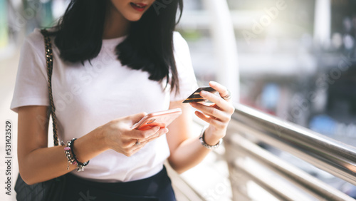 Adult woman consumer using creadit card and smartphone shopping via online application for spending money cashless.