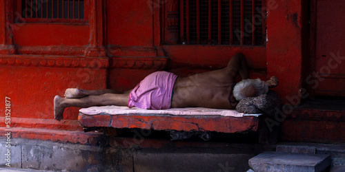 Hindu man with bare torso sleeping on a stone bench. Varanasi, Uttar Pradesh (India).