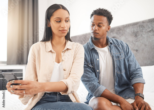 Social media, secret and liar woman with phone and man reading message, text or online post. Affair, cheating and jealous couple with no trust or faith in toxic marriage relationship in the bedroom