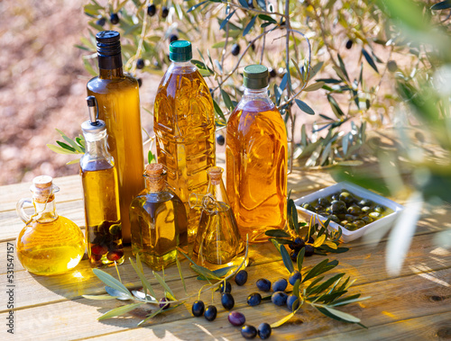 Olive oil on wooden table on background of olive tree. High quality photo