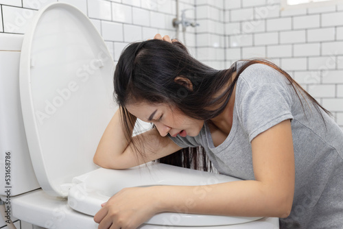 Asian Woman Vomiting into Toilet Bowl