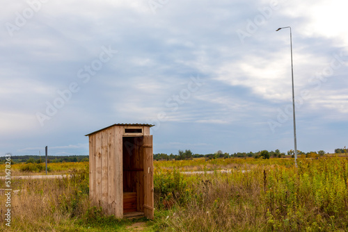 Wooden outhouse in a field, near a road in Ukraine