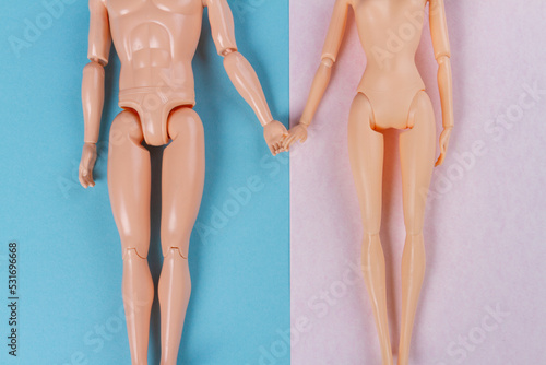 Top view naked doll couple holding hands. Blue and pink background.