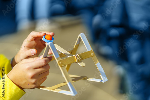 A child shoots plasticine from a homemade wooden catapult