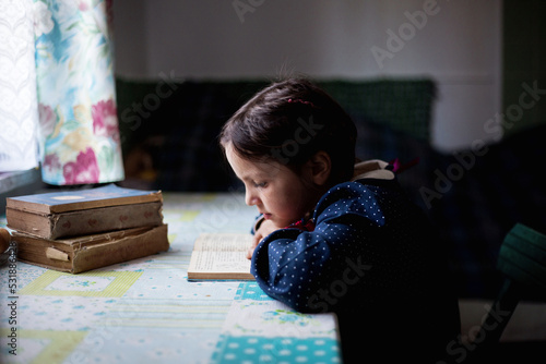 Mała dziewczynka odrabia lekcje i uczy się czytać