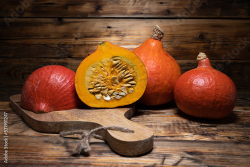 Hokkaido pumpkins on wooden background. Red kuri squash autumn fall rustic composition for Halloween or Thanksgiving.