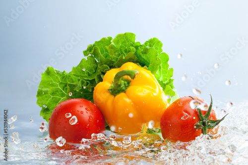 fresh vegetables in splashing water on blue background.