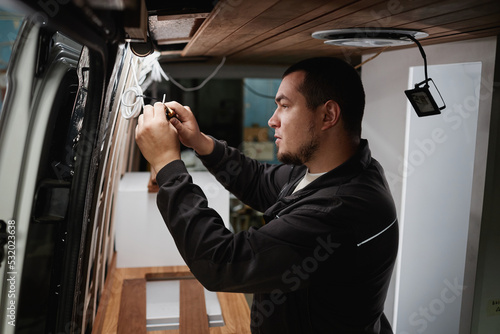 Side view portrait of man building camper van and installing wires for electrics