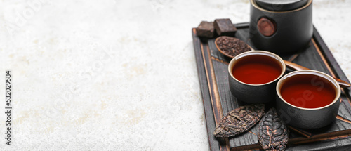 Cups of hot puer tea on light background with space for text