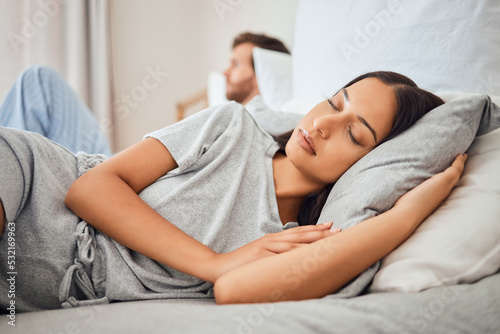 Sleeping, peace and woman asleep on bed with comfortable pillow while taking nap to relax with sleepless partner in background. Couple, sexual problems and carefree wife lying eyes closed next to man