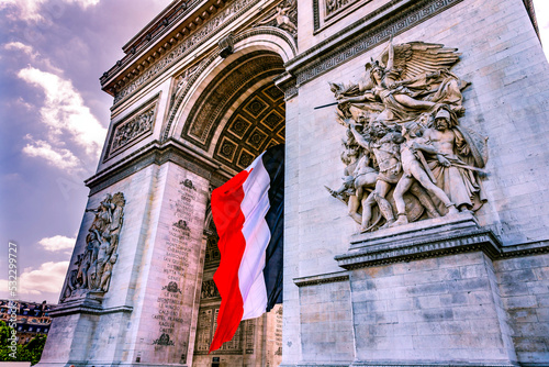 Arc de Triomphe and French flag, Paris, France. Completed in 1836 monument to the dead in the French Revolution and Napoleonic Wars. Includes Tomb to Unknown Soldier