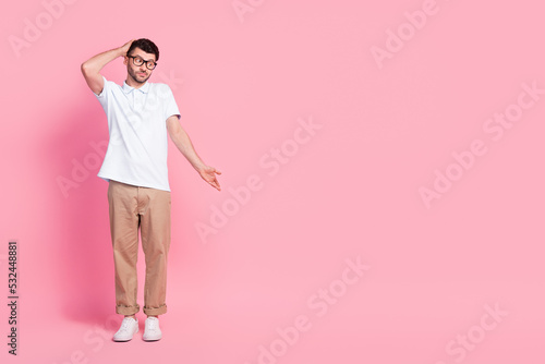 Full length photo of clueless attractive man stylish outfit look down arm direct empty space dont know isolated on pink color background