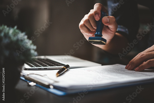 Man stamping approval of work finance banking or investment marketing documents on desk.