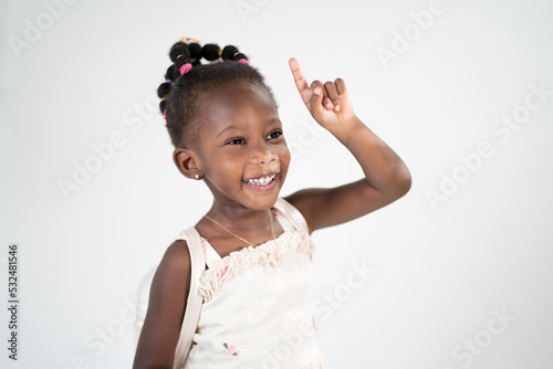 Una ragazzina sorridente in età scolare attira l'attenzione alzando il dito indice e indicando un posto per una scritta per pubblicità e sconti. Isolato su sfondo bianco