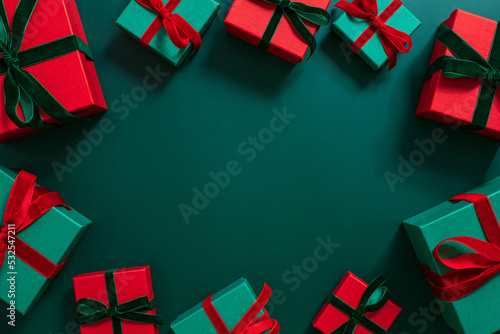 Gifts frame on a green background. Christmas or festive decorations. Green and red gift boxes. Copy space, top view, flat lay.