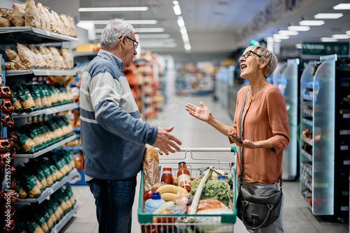 Displeased senior couple arguing while shopping in supermarket.
