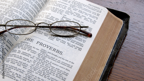 An old King James Bible on a table open to the book of Proverbs.