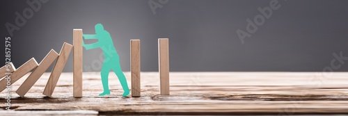 Green Paper Man Stopping Wooden Domino Blocks