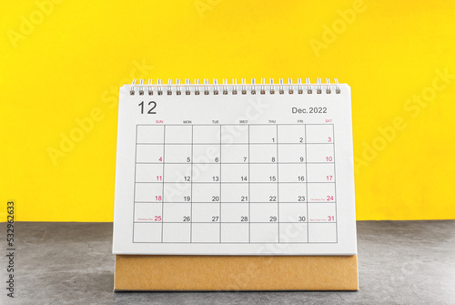 december calendar 2022 on the wooden table on a yellow background.