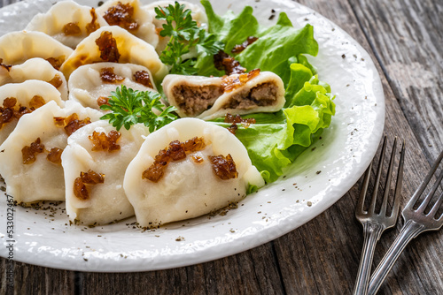 Dumplings - meat dumplings with onion and bacon on wooden table 