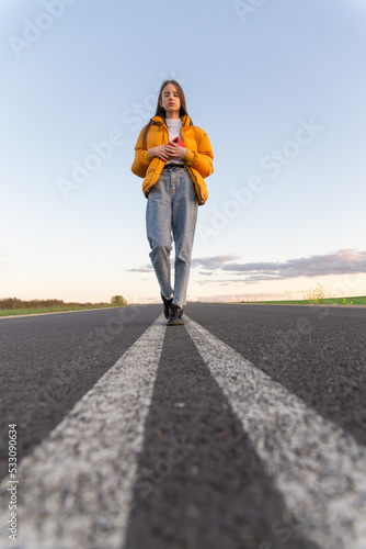 Cool modern teen girl poses on a lonely road