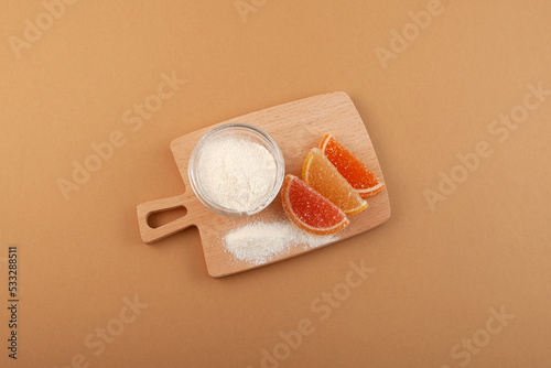 Pectin extract in bowl and Citrus jelly marmalade on wooden board, top view. Food additive E440. Citrus Pectin powder used as gelling, thickening and stabilizing agent in foods