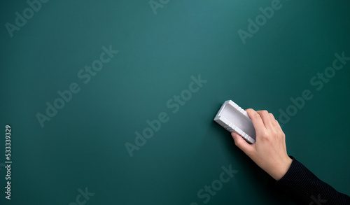 Hand holding brush erase on blackboard