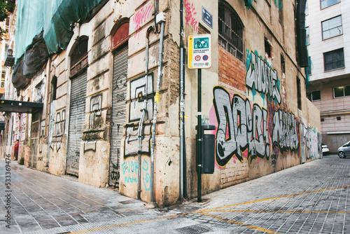 A grungy street corner with graffiti painted on the decaying wall