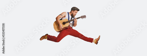Expressive musician wearing retro style clothes playing guitar like rockstar isolated on white background. Retro style, vintage fashion, music, art