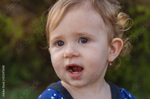 Baby plays snot in the street with a cold nose. Selective focus.