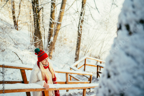 portrait of a girl in a red hat and scarf laughing in a snowy forest on a cold day