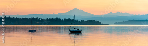 Colorful Sunrise Over Mt. Baker With a Sailboat in the Foreground. Beautiful calm morning in the San Juan Islands as the majestic Mt. Baker looms in the background.