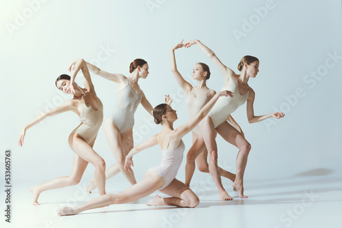 Group of young women, ballerinas dancing, performing isolated over grey studio backgroun. Contemporary art ballet