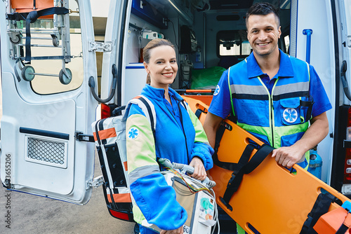 Emergency medical technicians standing near ambulance. Personnel of emergency service with first aid medical equipment